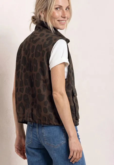 Femme de profil en T-shirt blanc, jean bleu et veste sans manches léopard marron