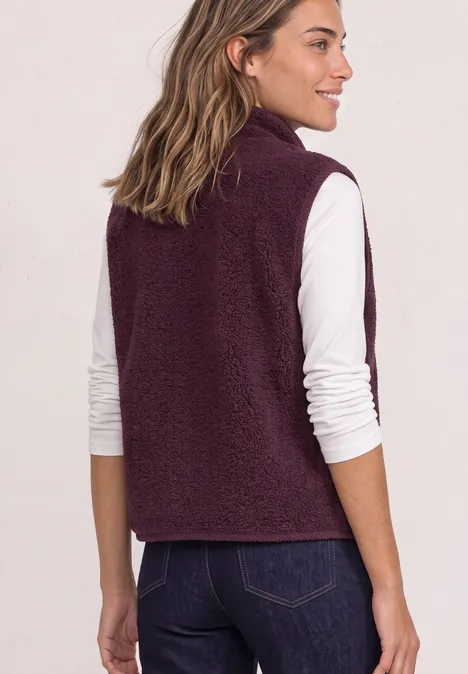 Frau von hinten in weißem Langarmshirt und dunkelroter Fleece-Weste, blickt nach links.