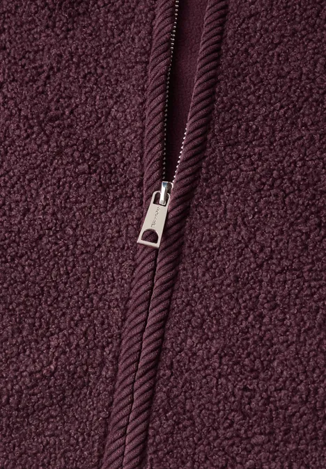 Nahaufnahme eines bordeauxroten Fleece-Stoffs mit Reißverschluss.