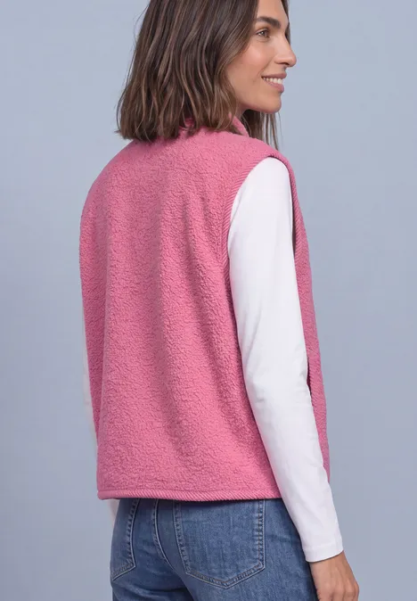 Frau von hinten in rosa Teddyweste über weißem Langarmshirt und blauer Jeans.