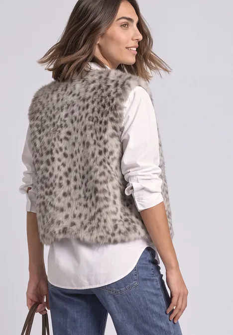 Fake-Fur Weste mit Zipper und Taschen clay sand Frau steht in Jeans und weißer Bluse, trägt eine gefleckte Kunstfellweste und hält eine Handtasche.