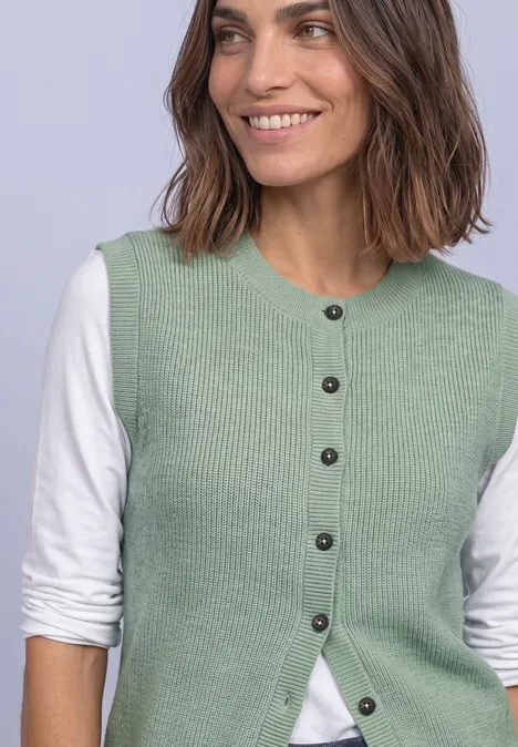 Strickweste mit Rundhals und Knopfleiste eucalyptus green mel. Lächelnde Frau in hellgrüner Strickweste und weißem Langarmshirt