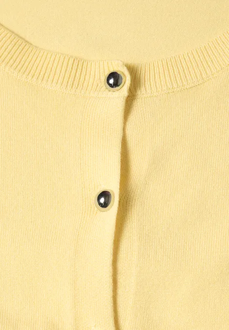 Close-up van een gele cardigan met zwarte knopen
