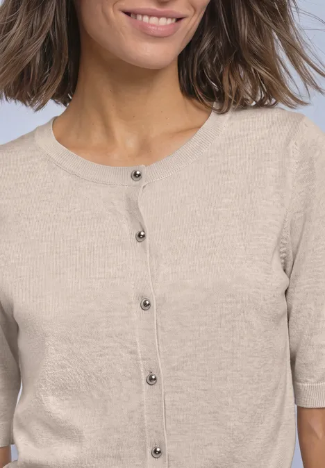 Beige vest met korte mouwen en zwarte knopen aan de voorkant.