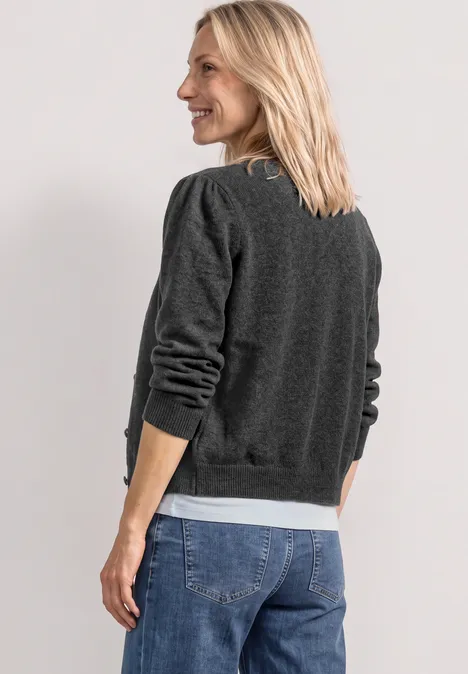 Langarm Cardigan mit Rundhals und Knöpfen armor grey mel. Junge blonde Frau von hinten, blickt über die Schulter, trägt grauen Pullover mit weißen Bündchen und Jeans.