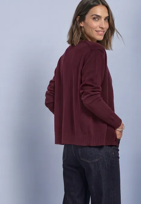Langarm Cardigan im offenen Schnitt rustic rouge Frau im weinroten Cardigan und Jeans blickt über die Schulter und lächelt vor hellem Hintergrund