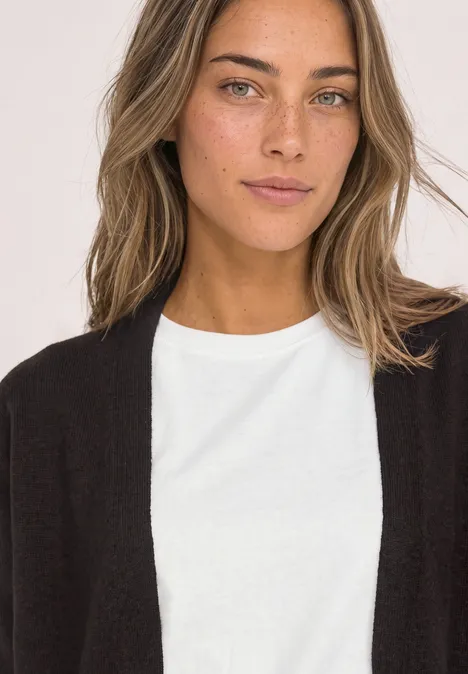 Langarm Cardigan im offenen Schnitt black coffee Frau mit schwarzem Cardigan und weißem T-Shirt, Schulterporträt vor hellem Hintergrund, leichtes Lächeln.