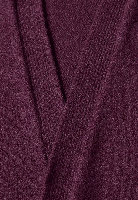 Nahaufnahme eines burgunderroten, gestrickten V-Ausschnitt-Pullovers mit feiner Maschenstruktur.