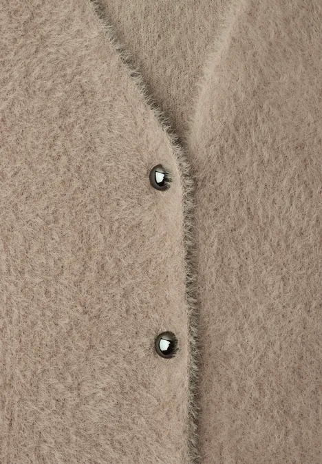 Beige Fluffy-Strickjacke mit zwei dunklen Knöpfen aus wolligem Material.