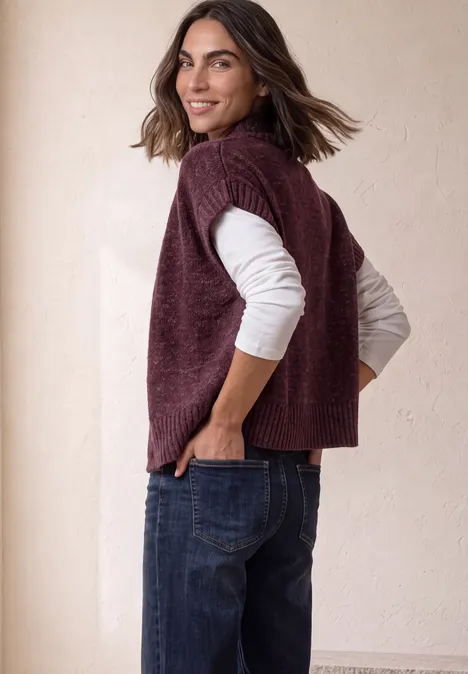 Dropped Shoulder Cardigan mit Turtle Neck und Zipper rustic rouge mel. Frau in Poncho-Top und Jeans dreht sich lächelnd zur Kamera.