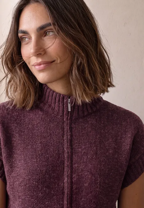 Dropped Shoulder Cardigan mit Turtle Neck und Zipper rustic rouge mel. Nahaufnahme einer Frau mit schulterlangen braunen Haaren und einem kurzärmligen, violetten Strickpullover mit Reißverschluss.