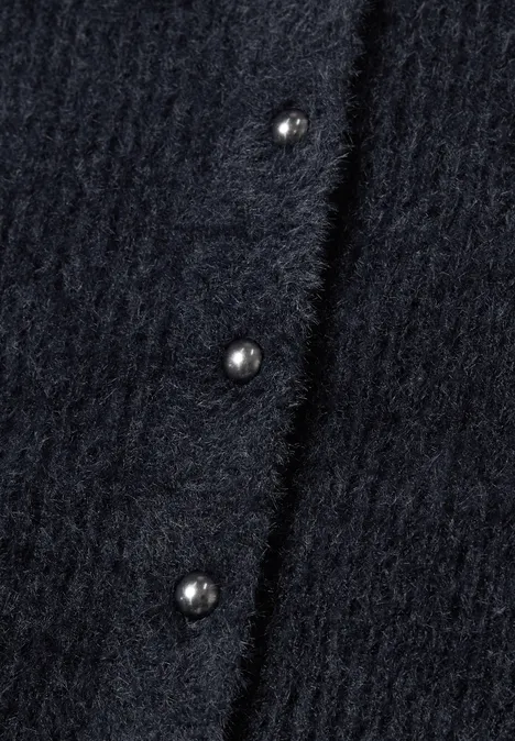 Detailaufnahme eines dunklen Wollcardigans mit perlmuttartigen Knöpfen.