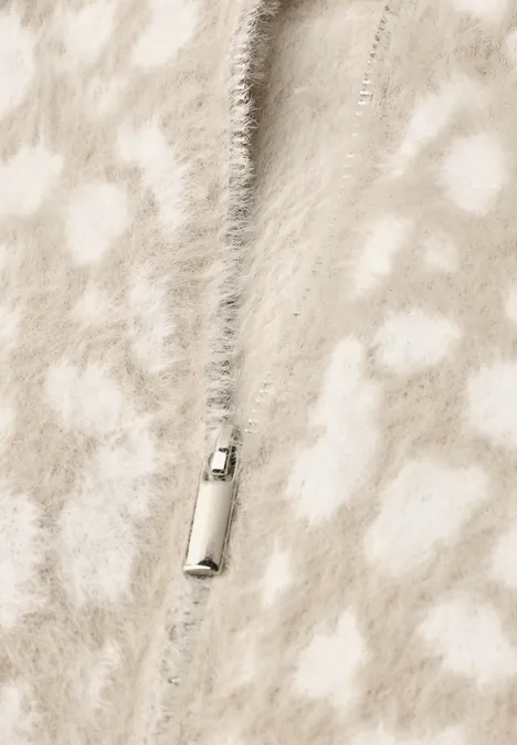 Beige-witte, pluizige gebreide jas met ritssluiting.