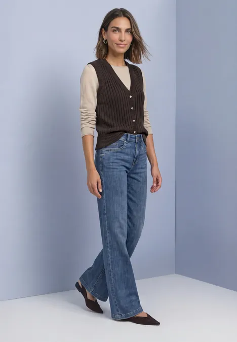 Weste mit V-Neck in Rippstruktur black coffee Frau in beigem Langarmshirt, brauner Strickweste, weiten Jeans und spitzen Ballerinas.
