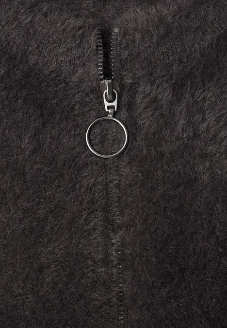 Flauschiger, schwarzer Stoff mit einem Reißverschluss und rundem Zipper-Anhänger.
