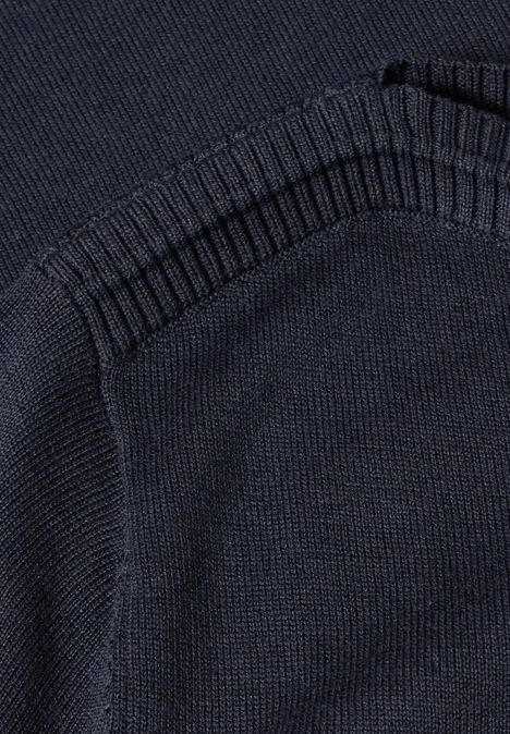 Nahaufnahme eines dunkelblauen Strickpullovers mit einer aufgesetzten Tasche und Rippstrickbündchen.