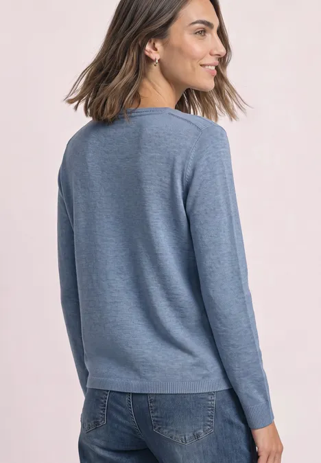 Pull basique à col bateau northern blue mel. Femme de profil portant un pull bleu clair décontracté et un jean.