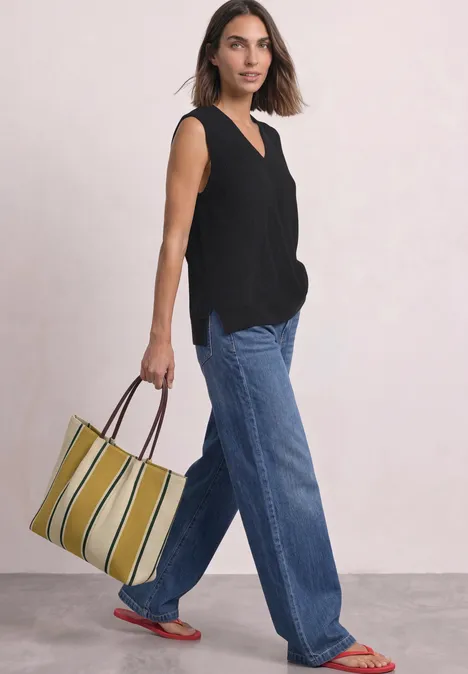 Pullunder mit V-Neck in Unifarbe Black Eine Frau in schwarzem Top und weiten Jeans trägt eine gestreifte, gelb-grüne Tasche.