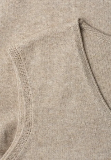 V-hals trui in effen kleur light sepia sand mel. Nahaufnahme eines beige gestrickten, ärmellosen V-Ausschnitt-Oberteils.