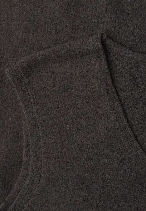 V-hals trui in effen kleur black coffee mel. Nahaufnahme eines dunklen Kleidungsstücks aus Strickstoff mit sichtbarer Naht und Tasche.