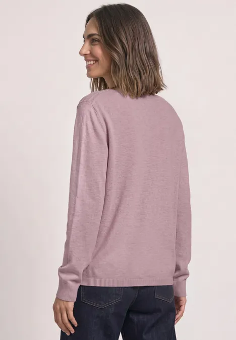 Basic Pullover mit U-Boot-Ausschnitt quiet rose mel. Frau von hinten, trägt rosafarbenen Langarmpullover und dunkle Jeans, lächelt seitlich.