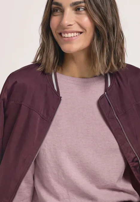 Basic Pullover mit U-Boot-Ausschnitt quiet rose mel. Lächelnde Frau mit schulterlangen Haaren trägt rosa T-Shirt und bordeauxrote Jacke.