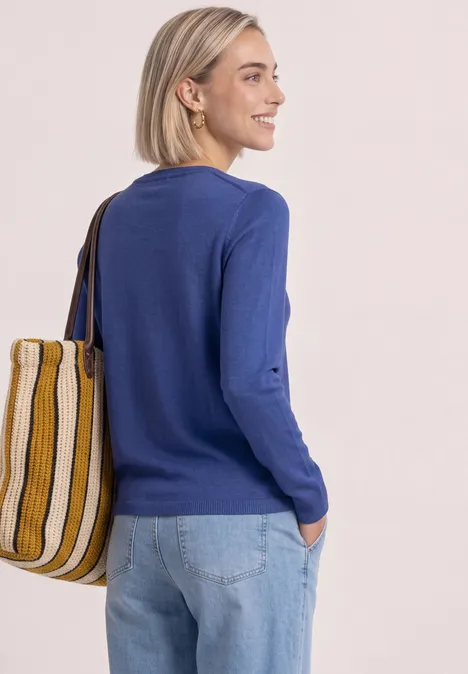 Eenvoudige trui met boothals bold blue Vrouw in blauwe trui en spijkerbroek met gestreepte tas, staand voor een lichte muur.