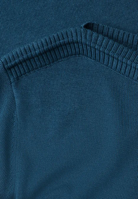 Nahaufnahme eines blau-grünen Strickpullovers mit Rippenstrickabschluss am Halsausschnitt.