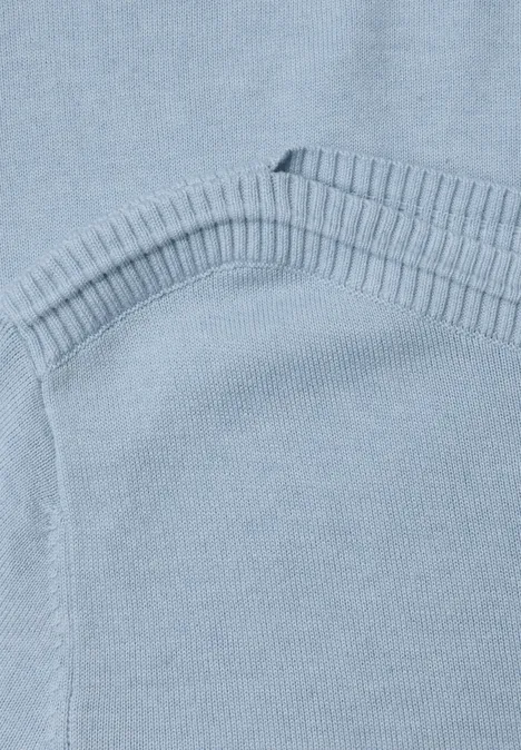 Eenvoudige trui met boothals pale blue mel. Close-up van een lichtblauwe gebreide trui met geribde boord en zichtbare naad