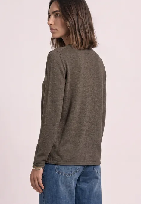 Trui met ronde hals en omgeslagen randen nomad brown mel. Vrouw in een bruin shirt met lange mouwen en blauwe jeans, schuin van achter gefotografeerd tegen lichte achtergrond.
