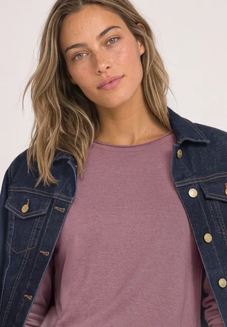 Frau mit Jeansjacke über rosafarbenem Shirt, welliges Haar, natürlicher Look