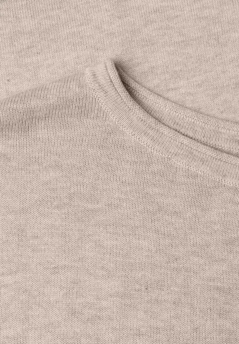 Trui met ronde hals en omgeslagen randen clay sand mel. Close-up van een beige T-shirt met ronde hals en fijne gebreide textuur.