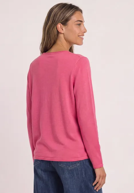 Trui met ronde hals en omgeslagen randen impact pink Vrouw van achteren in een roze longsleeve en donkere spijkerbroek tegen lichte achtergrond.
