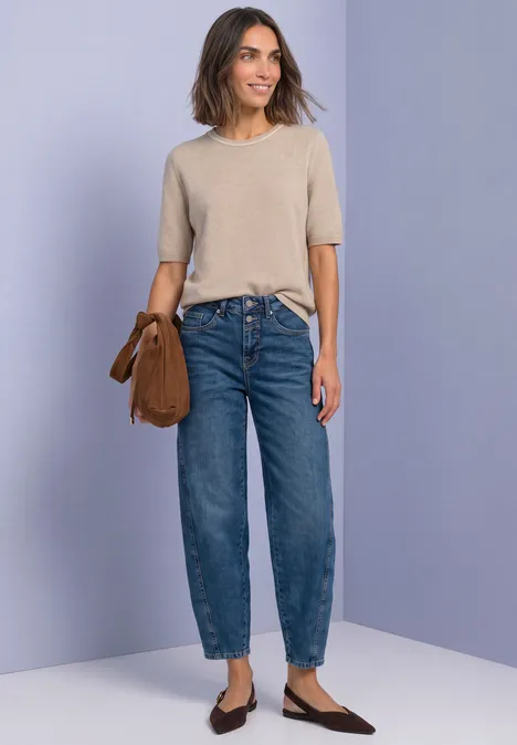 Kurzarm Pullover mit Kontrastdetail clay sand mel. Frau in beige T-Shirt, blauen Jeans und braunen Loafers posiert mit Schultertasche vor schlichter Wand.