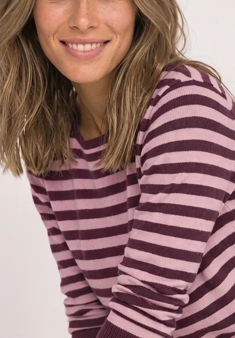 Pullover mit Boat Neck und Streifen rustic rouge mel. Eine lächelnde Frau in einem lila-pink gestreiften Langarmshirt.