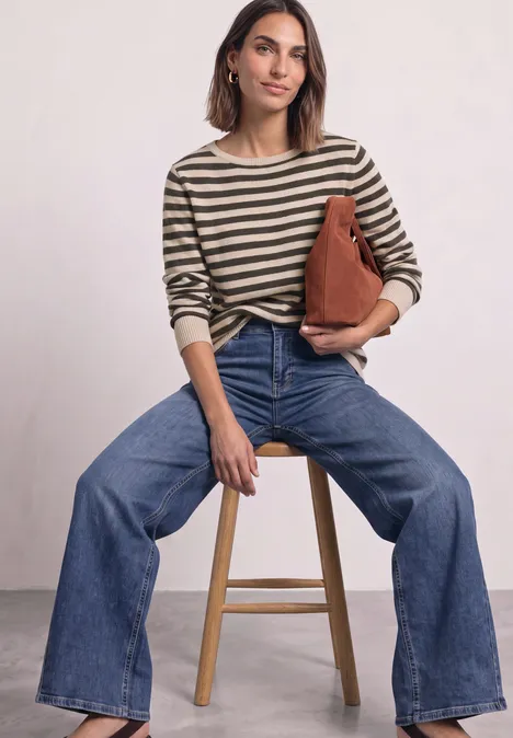 Pullover mit Boat Neck und Streifen clay sand mel. Frau sitzt auf Hocker, trägt gestreiften Pullover, weite Jeans und hält eine braune Tasche.