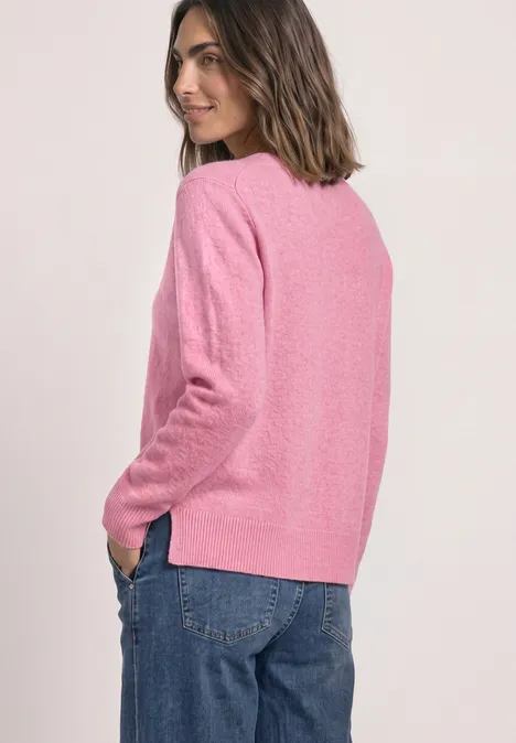 Femme en pull rose et jean, vue de dos, souriante, style décontracté.