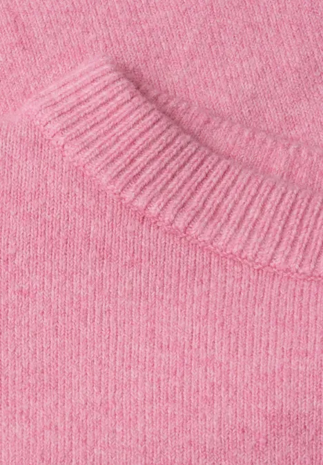 Gros plan sur un pull en maille rose pastel à la texture douce et finement tricotée.