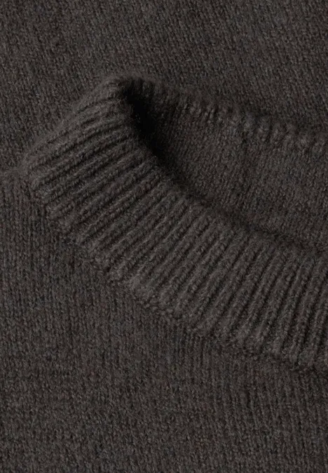 Gros plan sur un pull en maille marron avec col côtelé et texture douce.