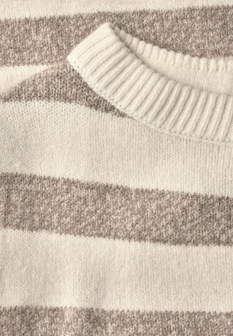 Nahaufnahme eines gestrickten Pullovers mit breiten creme- und hellbraunen Querstreifen.