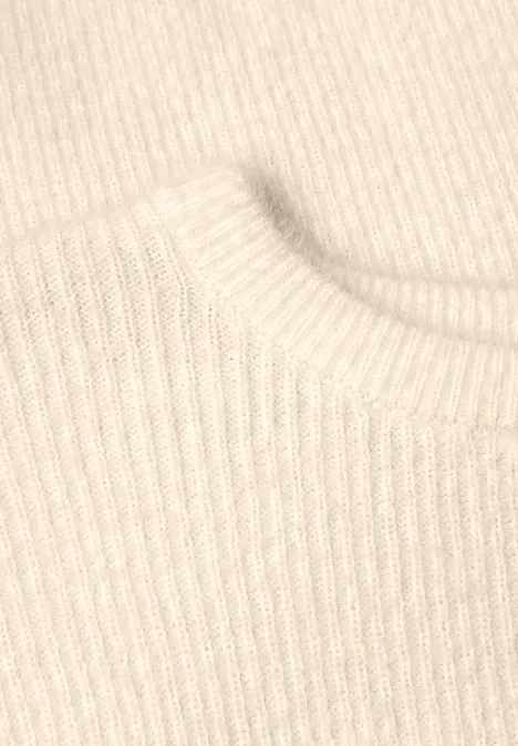 Gros plan sur un tissu tricoté beige à côtes, probablement le col d’un pull.