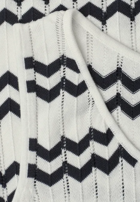 Nahaufnahme eines weißen Stricktops mit schwarzen Zickzackstreifen