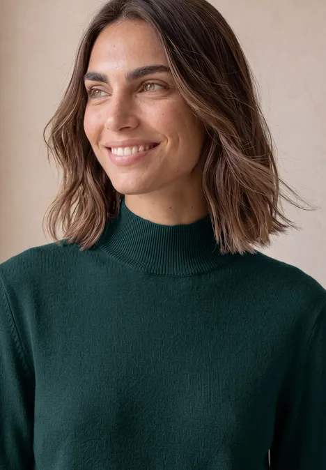 Basic Pullover mit Turtle Neck shadow teal Lächelnde Frau mit schulterlangen braunen Haaren und grünem Rollkragenpullover vor hellem Hintergrund.