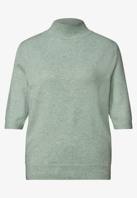 Hellgrüner Pullover mit hohem Kragen und halblangen Ärmeln.