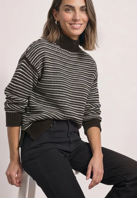 Pullover mit Turtle Neck und Streifenmuster black coffee Frau sitzt lächelnd in gestreiftem Pullover und schwarzen Hosen
