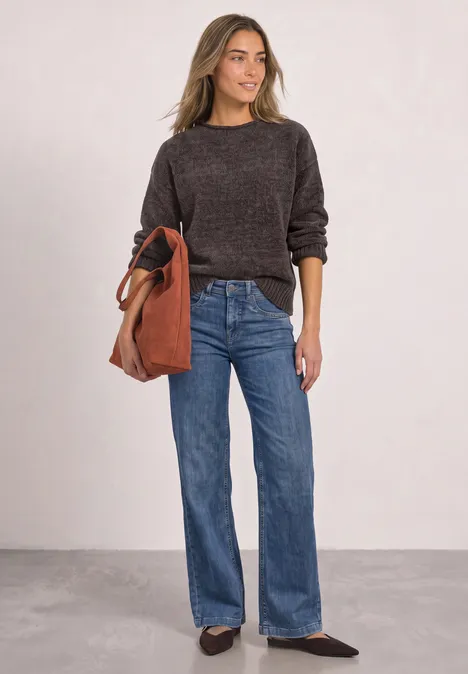 Chenille-Pullover mit U-Boot-Ausschnitt black coffee Frau im braunen Pullover, weitem Jeans, Slingback-Schuhen und roter Ledertasche vor neutralem Hintergrund.