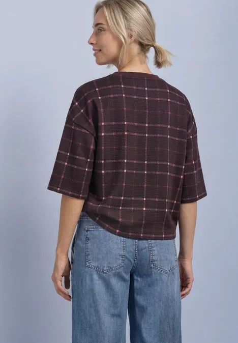 Frau von hinten in lässigem karierter Kurzarmshirt und weiten Jeans