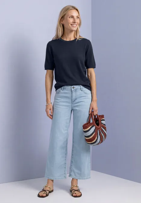T-shirt met korte mouwen en ronde hals in effen kleur darkest blue Vrouw draagt zwart T-shirt, lichte wijde jeans en sandalen, met een gestreepte handtas.