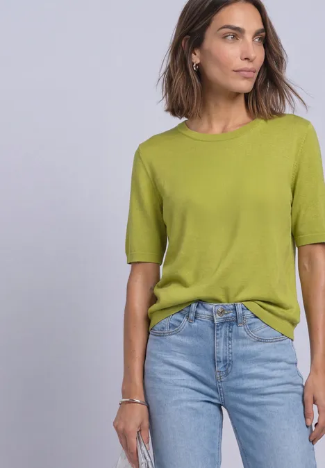 T-shirt met korte mouwen en ronde hals in effen kleur apple lime Een vrouw met halflang bruin haar draagt een lichtgroen T-shirt en blauwe jeans tegen een lichte achtergrond.