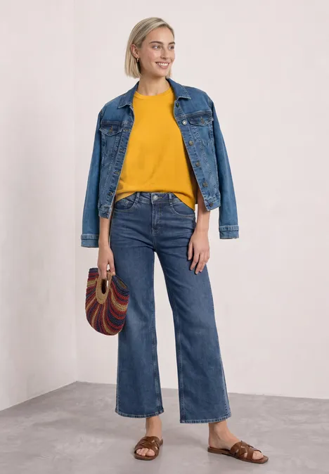 T-shirt met korte mouwen en ronde hals in effen kleur saffron yellow Een vrouw draagt een gele trui, wijde jeans, spijkerjasje en handtas.